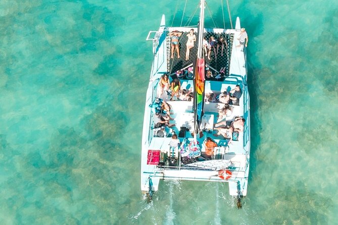 Catamaran anchored off Dragon Island in Dakhla Bay with pink flamingos wading in shallow turquoise water