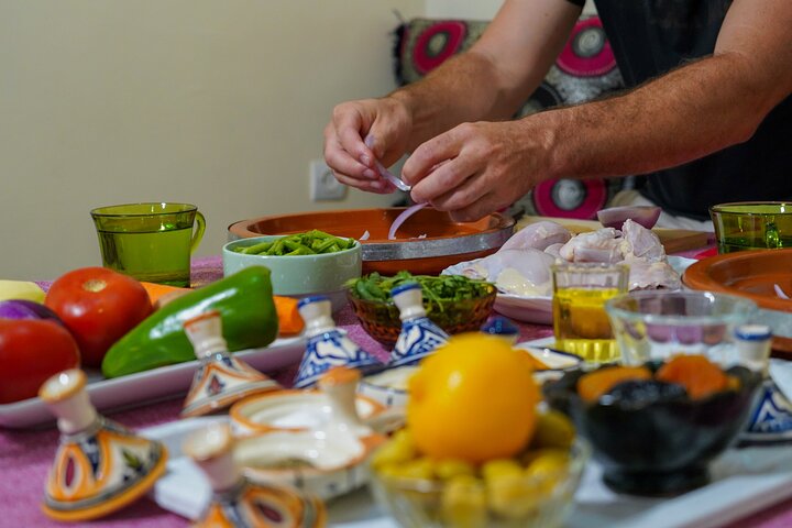 Local host and traveler preparing a fresh seafood tagine with spices in an Essaouira cooking workshop