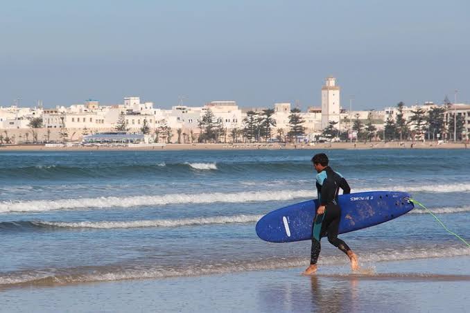 Surf instructor and student with soft-top surfboards on Essaouira's main sandy beach at low tide